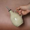 Bouteille à huile en grès fait main dans la Loire tenue par une main pour montrer sa taille.